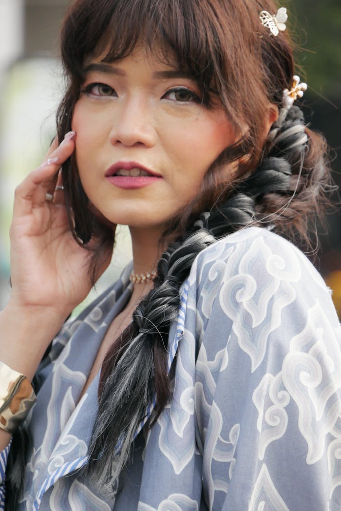Stylish woman wearing a traditional patterned dress with braided hairstyle, outdoors.